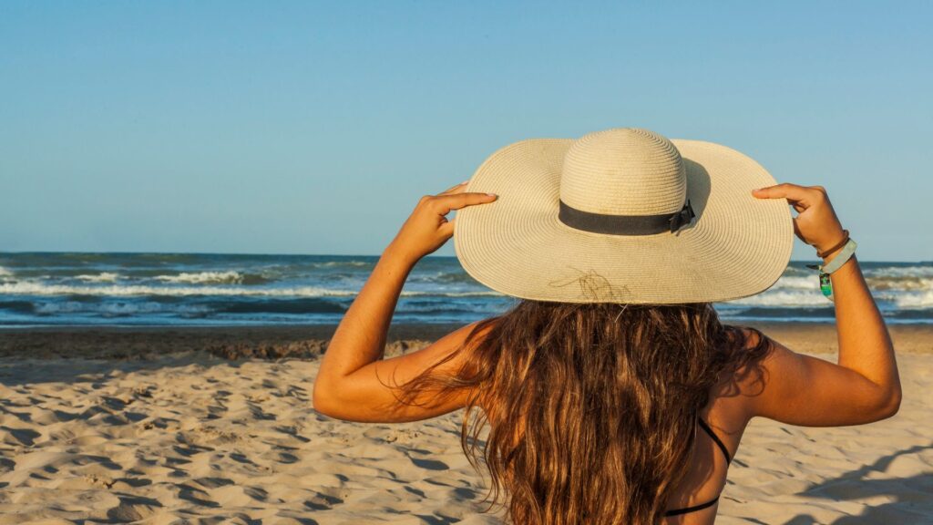Women in the sun at beach with hat